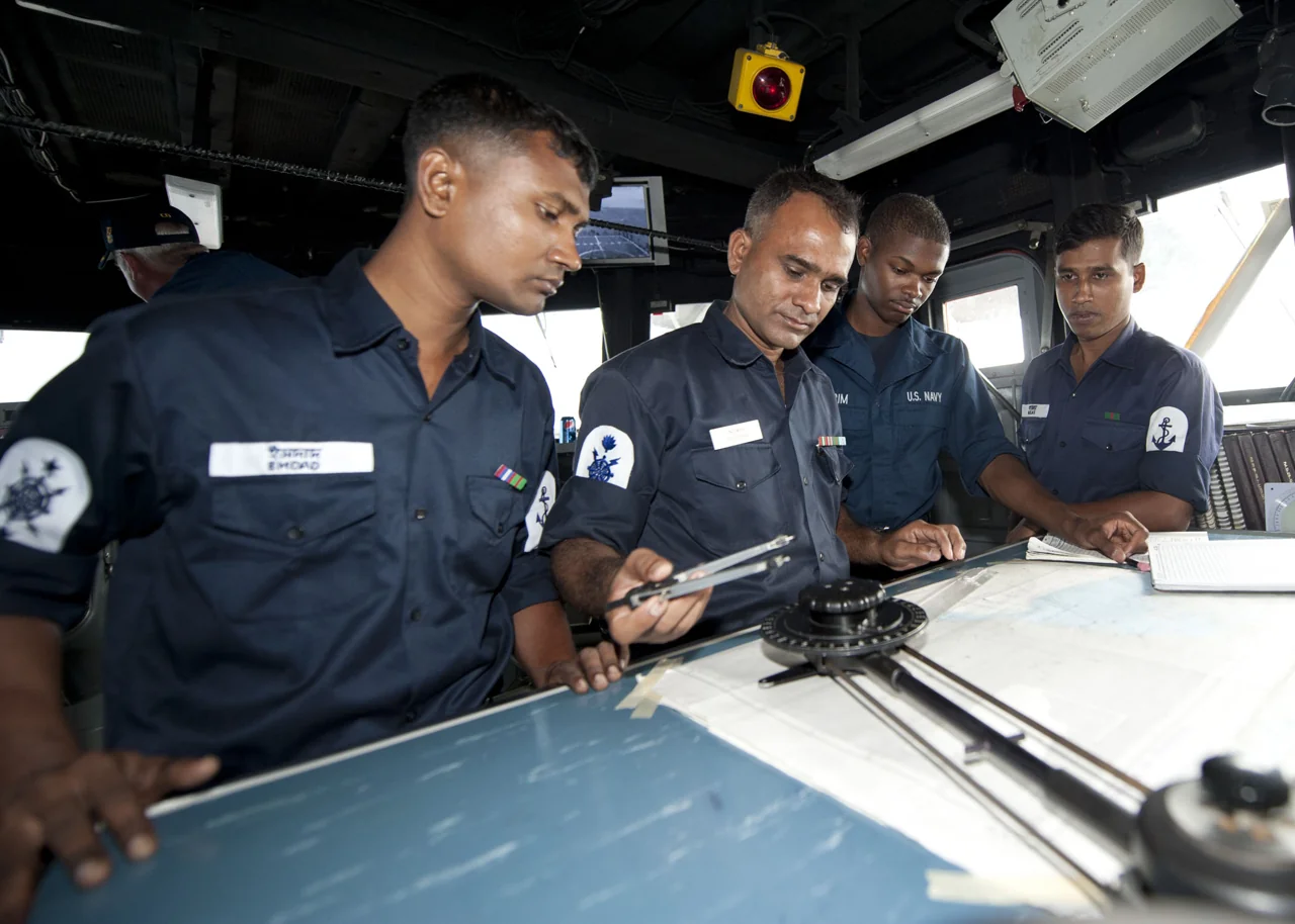 Bangladesh Navy sailors study a navigation chart aboard USS Ford in 2011 (archival photograph).