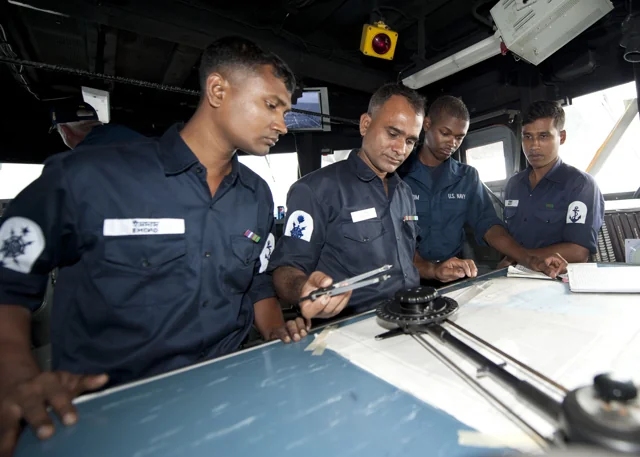 Bangladesh Navy sailors study a navigation chart aboard USS Ford in 2011 (archival photograph).
